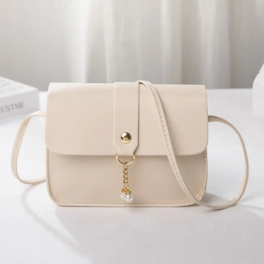 Small structured shoulder bag in soft pink worn crossbody with minimalist outfit