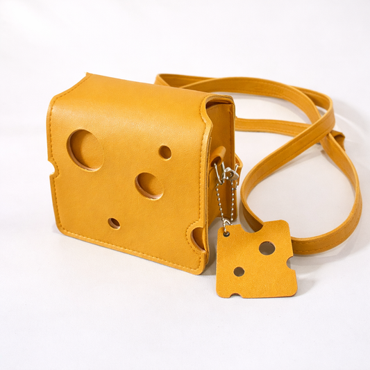 Yellow novelty crossbody bag with playful sculpted shape and adjustable strap on white background