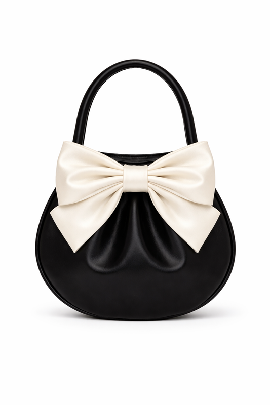 Black patent mini hobo bag with oversized cream bow and top handle on white background