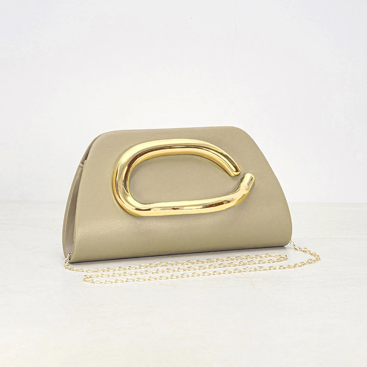 Women holding ivory clutch with oversized gold metal detail and slim structured silhouette for evening styling