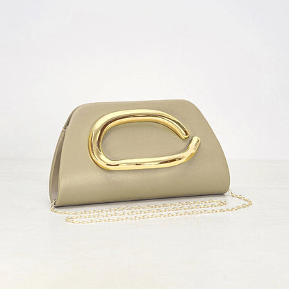 Women holding ivory clutch with oversized gold metal detail and slim structured silhouette for evening styling