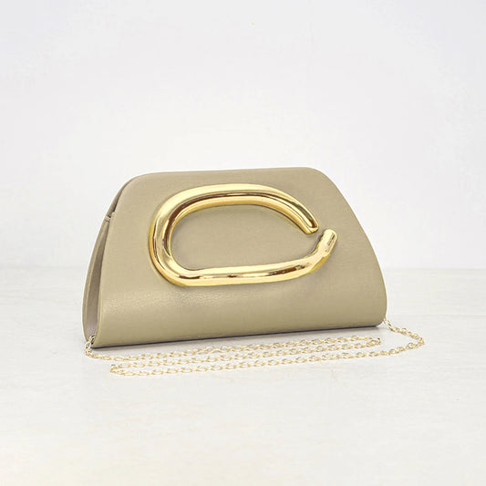 Women holding ivory clutch with oversized gold metal detail and slim structured silhouette for evening styling