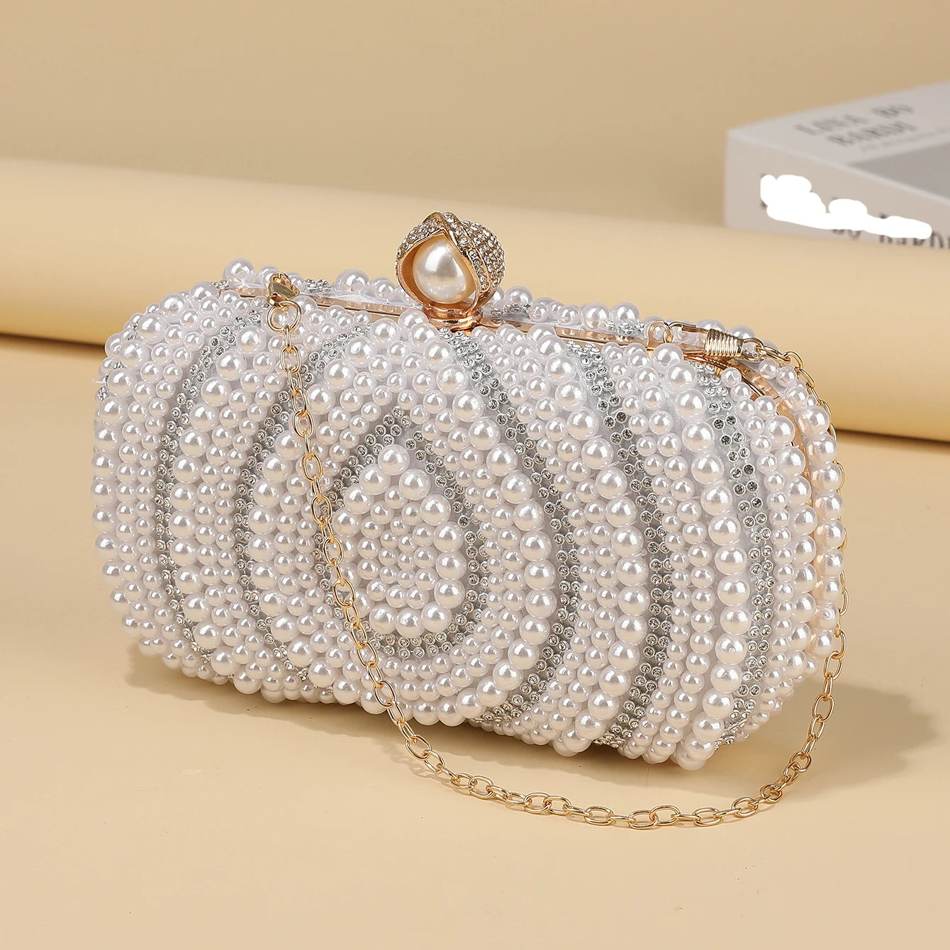 Luminous pearl beaded evening clutch showing structured frame closure and chain strap detail, formal women’s party handbag