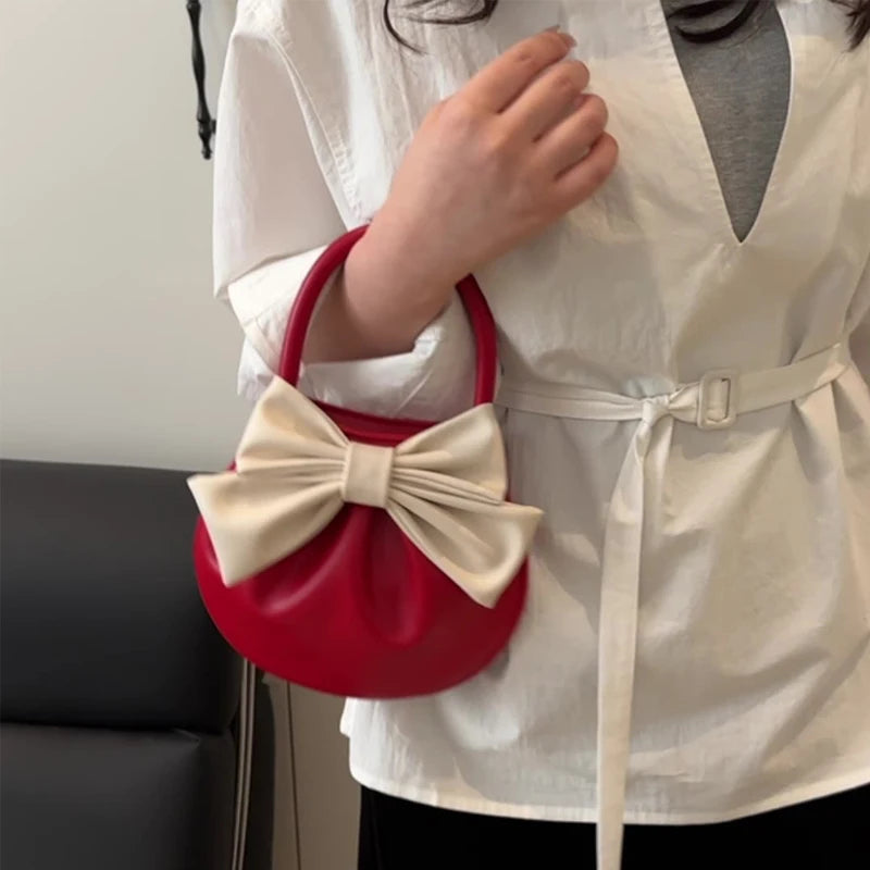 Woman carrying a bow detail mini handbag in black and cream styled for a chic outfit