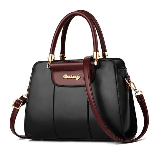 Structured black and burgundy satchel handbag with top handles and crossbody strap on white background