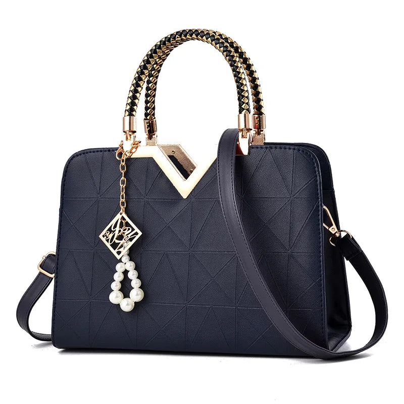 Navy structured satchel handbag with gold V handle and charm accessory, elegant women’s top handle shoulder bag
