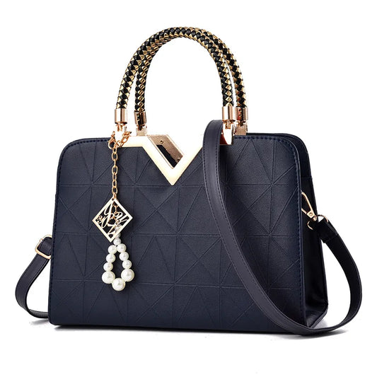 Navy structured satchel handbag with gold V handle and charm accessory, elegant women’s top handle shoulder bag