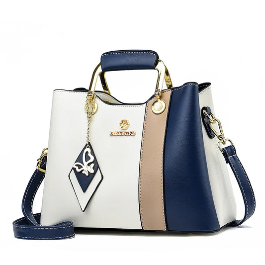 Colorblock satchel handbag with navy, white, and tan panels and gold hardware, structured women’s crossbody shoulder bag